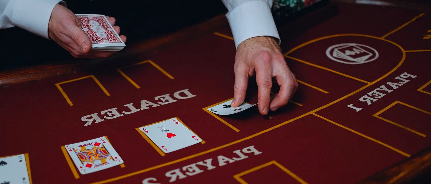 A gloved hand dealing cards across the felt